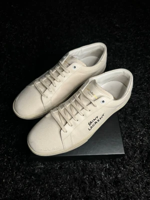 Saint Laurent canvas sneakers - Snygga vita sneakers från Saint Laurent i canvasmaterial med handskriven logga på sidan. Väldigt fint skick, box medföljer. Skriv för fler frågor 😊