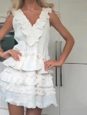 Vit volangklänning med v-ringning - Supersöt vit kortklänning med flera volanger. Perfekt för studenten eller bara sommaren. Aldrig använd. Vid snabb affär kan pris diskuteras.  🙌LÅNADE BILDER🙌