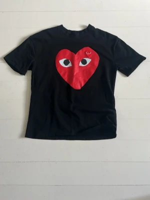 Cdg T-shirt - Hej, säljer denna Comme des garcons T-shirten pga att jag har växt ur den. T-shirten har inga defekter eller något strul. Den är använder fåtal gånger och passar dig perfekt som är 175-180cm och väger runt 63-75