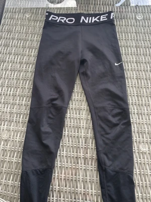 Nike Pro svarta leggings - Snygga svarta träningstights från Nike Pro med bred resår i midjan där det står 'NIKE PRO'. Märket är lite slitet. Stl 146/152. 