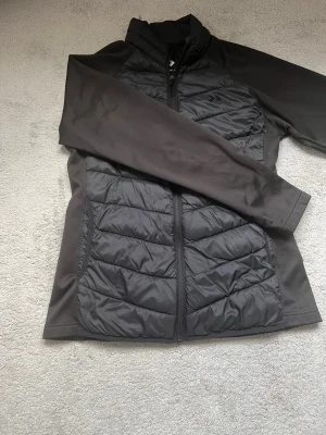 Svart pufferjacka  - Snygg svart pufferjacka från 157  med quiltad front och rygg samt släta ärmar. Jackan har hel dragkedja, hög krage och är tillverkad i ett lätt, vadderat material som håller värmen. Perfekt för kalla vinterdagar och enkel att matcha med olika outfits.