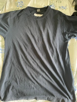 Svart t-shirt från ID Pro Wear - En enkel svart t-shirt från ID Pro Wear i klassisk modell. T-shirten har rund halsringning och korta ärmar. Tillverkad i mjuk bomull som känns skön mot huden. Perfekt basplagg att ha i garderoben.