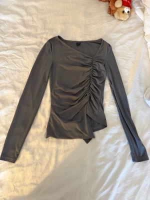 Grå långärmad topp med rynk - Grå långärmad topp med asymmetrisk nederkant och rynkdetalj framtill. Från shein storlek xs