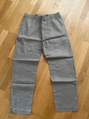 Beiga linnebyxor från H&M Regular Fit - Snygga beiga linnebyxor från H&M i modellen Regular Fit. Byxorna har resår i midjan, raka ben och sidofickor. Perfekta för en avslappnad och stilren look. Materialet är luftigt linne som passar bra till varmare dagar.