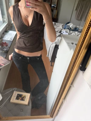 Brun omlottopp med v-ringning💕 - Snygg brun omlottopp med djup v-ringning och ärmlös design. Toppen har en croppad passform som framhäver midjan och är perfekt för att styla med jeans eller kjol. Materialet känns mjukt och följsamt mot kroppen!!❤️