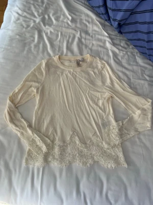 Vit långärmad topp med spetskant - Säljer en söt vit långärmad topp från H&M med spetskant längst ner på ärmar och nederkant🤍🤍Storlek XS
