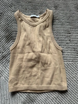 Beige ribbad linnetopp från stradivarius  - Säljer en beige ribbad linnetopp från stradivarius. Toppen är ärmlös med breda axelband och har en enkel, croppad passform som är perfekt för varma dagar. Materialet är mjukt och stretchigt, vilket gör den bekväm att bära. OBS: FRAKTAR INOM 24H!🩷