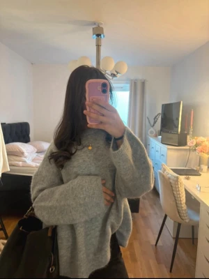 Ljusgrå oversized stickad tröja - Mysig ljusgrå stickad tröja i oversized modell med breda ärmar och rund hals. Tröjan har en fluffig struktur och är perfekt för lager på lager. Passar dig som gillar en avslappnad och trendig stil. Den är även köps för 1200 kronor 