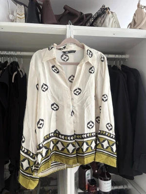 Vit satin skjorta  - Säljer en vit satin skjorta från Zara med svart och gul geometriskt mönster. Perfekt skönt material till sommaren