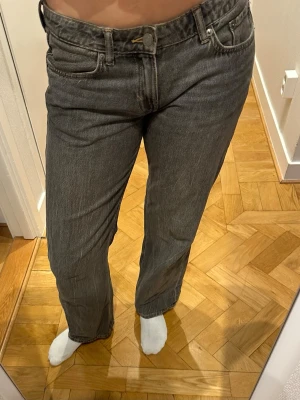 Grå raka jeans med låg midja  - Säljer ett par grå jeans med rak passform och låg midja. Klassisk femficksmodell med bälteshällor och knappgylf. 