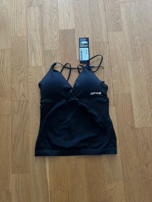 DFYNE Vision Twist Front Lingline Top - Säljer ett DFYNE Vision Twist Front Longline Top i färgen ”Midnight Black” med inbyggd sport-bh i st S, oanvänd med lappen kvar. Original pris 55,95€ - ca 610kr.