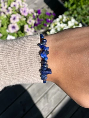 Blått armband med stenar och pärlor - Snyggt armband med oregelbundna blå stenar och små runda pärlor på blå tråd. Justerbar knytning för perfekt passform. Perfekt accessoar för dig som gillar unika smycken med naturlig känsla.