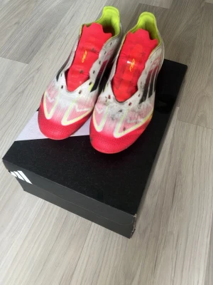 Adidas X Speedflow fotbollsskor - Säljer ett par Adidas X Speedflow fotbollsskor med en grymt snygg design i rött, vitt och neon-gult. Skorna har en låg profil, lätta material och klassiska svarta Adidas-stripes på sidan. Perfekta för snabba spelare som vill ha bra grepp och känsla på planen.