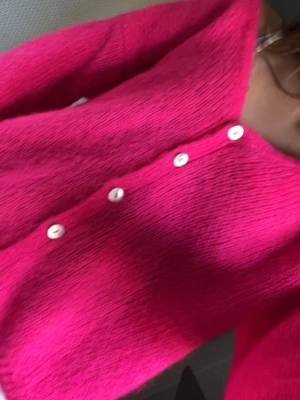 Rosa kofta med vita knappar - Superfin viral rosa kofta med v-ringning och fem vita knappar framtill. Koftan har en lös och mysig passform med ribbade muddar vid ärmslut och nederkant. Perfekt för dig som vill ha en färgklick i garderoben! Står inte riktigt storleken men skulle säga S. Ge gärna prisförslag men den är köpt för ungefär 700 i Paris och aldrig använd 