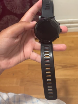 Svart smartklocka med silikonarmband - Snygg svart smartklocka med rund urtavla och silikonarmband. Klockan har flera knappar på sidan och pulsmätare på baksidan. Passar perfekt för dig som vill ha koll på träning och notiser direkt på handleden.