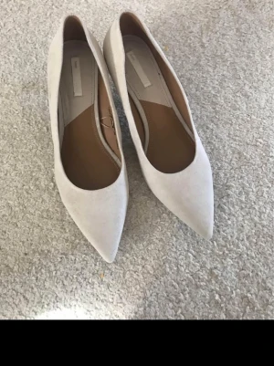 Beige spetsiga pumps från H&M - Snygga pumps i beige mockaimitation från H&M med spetsig tå och låg klack. Skorna har en stilren och klassisk design som passar till många olika outfits. Perfekta för dig som gillar en enkel men elegant look.