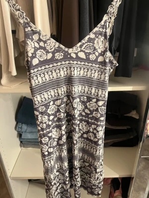 Blommigt nattlinne med spetsband - Snyggt nattlinne med smala spetsband och v-ringning. Mörkblå botten med vitt blommönster och dekorativa ränder. Mjuk och lätt material, perfekt för att chilla hemma. Lång modell som ger en avslappnad känsla.