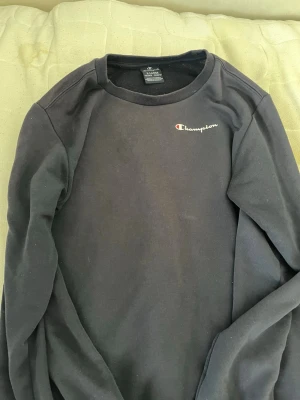Svart sweatshirt från Champion - Säljer en mörkblå och ljusgrön sweatshirt från Champion med klassisk logga broderad på bröstet. Tröjan har rund halsringning och långa ärmar. Perfekt för en avslappnad och sportig stil. Pris kan diskuteras.