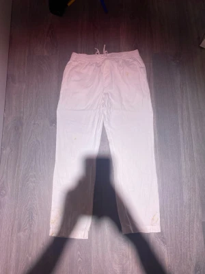 Vita linnebyxor med dragsko - Säljer ett par vita linnebyxor med avslappnad passform och dragsko i midjan. Byxorna har raka ben och är tillverkade i ett lätt och luftigt linnematerial, perfekta för en chill och stilren look. Inga synliga loggor eller märken.