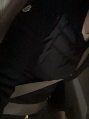 Svart Cardigan från Moncler - Svart Cardigan från Moncler med quiltad design och dragkedja framtill. Cardiganen har en hög krage och den klassiska Moncler-loggan på armen. Tillverkad i glansigt/matt material som ger en modern känsla.