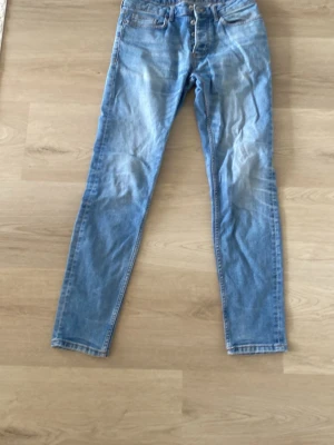 Ljusblå slim fit jeans - Säljer ett par ljusblå slim fit jeans med klassisk femficksdesign och dragkedjegylf. Jeansen har snygga slitningar och tvättade detaljer framtill och baktill för en trendig look. Perfekta till sneakers eller boots. W30 L32
