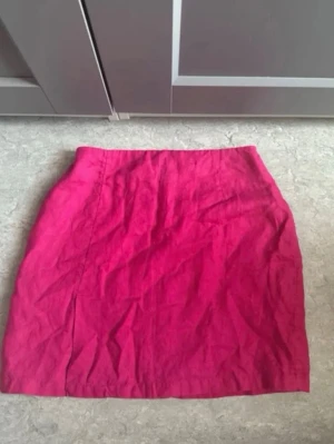 Rosa linnekjol med dragkedja - Snygg rosa kjol i linne med rak passform och dragkedja bak. Kjolen är enkel och stilren, perfekt för dig som gillar färg och vill ha en klassisk kortkjol till sommaren.