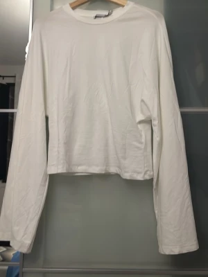Vit långärmad topp i bomull - En enkel och stilren vit långärmad topp med rund hals. Tillverkad i mjuk bomull och har en rak passform som passar till det mesta. Perfekt basplagg att ha i garderoben.