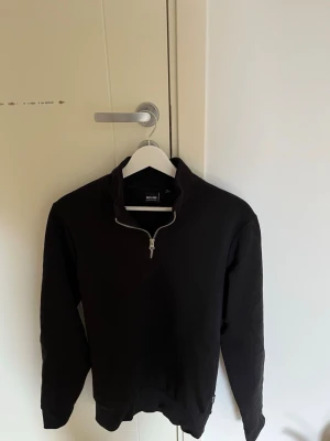 Svart half-zip tröja Only&Sons - Snygg svart långärmad tröja från Only&Sons med half-zip dragkedja vid halsen. Tröjan har en enkel och clean design med ribbade muddar vid ärmslut och nederkant. Perfekt för en avslappnad och stilren look. Använd ett fåtal gånger, inga synliga defekter eller fläckar. 