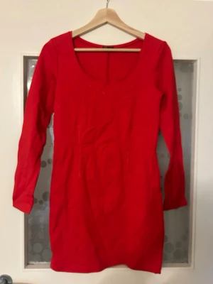 Röd långärmad klänning Filippa K - En enkel och stilren röd klänning från Filippa K med lång ärm och rundad urringning. Klänningen är kort i modellen och har en smickrande passform. Perfekt för dig som gillar minimalistisk design och vill ha en färgstark look.
