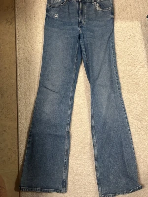 Blå bootcut jeans - Ett par blå bootcut jeans med lätt slitna detaljer vid fickorna. 