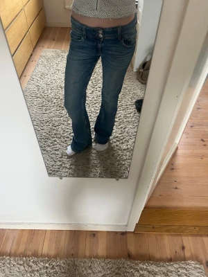 Blå bootcut jeans med låg midja - Säljer ett par jättefina blå bootcut jeans med låg midja och knapp fickor. Jeansen är lite slitna längst ner (man kan se på sista bilden). Skulle säga att de är små i storleken. Skriv ifall fler frågor!🩷🩷