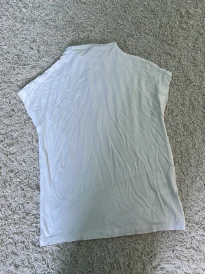 Vit basic t-shirt i bomull - En enkel vit t-shirt med korta ärmar och rak passform. Tillverkad i mjuk bomull, perfekt för en clean och avslappnad stil. Passar till allt och är ett måste i garderoben.