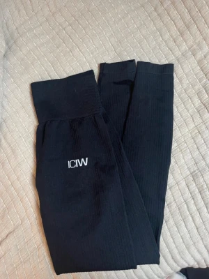 Svarta ribbade leggings från ICANIWILL - Svarta leggings från ICANIWILL med ribbad struktur och hög midja. Stretchigt material som sitter skönt och följsamt. Diskret logga framtill på benet. Perfekta för träning eller chill.    Inga tecken på användning, använt fåtal gånger. Lite noppriga. Nypris är 699 kr på deras hemsida☺️