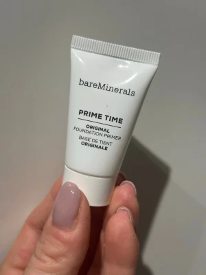 bareMinerals Prime Time Primer 15ml - bareMinerals Prime Time Original Foundation Primer i en vit tub. Primern är genomskinlig och hjälper till att jämna ut huden innan foundation. Perfekt för att få sminket att sitta längre och ge en slät finish. Smidig att ta med i necessären.