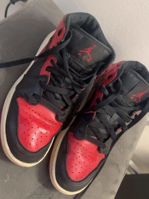 Air Jordan 1 High röd/svart - Säljer ett par klassiska Air Jordan 1 High sneakers i rött och svart läder med vita sulor. Dom är ju välanvända och som man ser på sulan är dom sönder och där av det billiga priset 