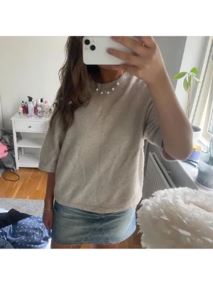 Beige stickad tröja med 3/4-ärm - Mysig beige stickad tröja med rund halsringning och 3/4-långa ärmar. Tröjan har en avslappnad passform och ribbstickad kant vid halsen. Perfekt att styla med jeans eller kjol för en enkel och trendig look.