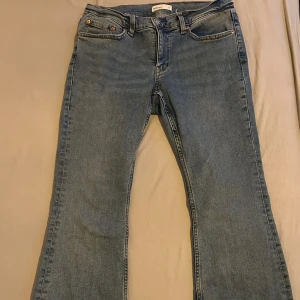 Blåa jeans  - Snygga blå jeansbyxor med klassisk design. De är bootcut jeans och är perfekta för en avslappnad stil. Byxorna har fem fickor och en knappgylf.