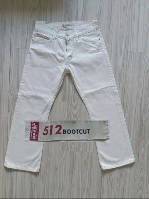 Vita Levi's 512 Bootcut jeans - Snygga sällsynta jeans från Levi's i modellen 512 Bootcut. Klassisk femficksdesign med normalhög midja och utsvängda ben. Perfekta för dig som gillar en retrostil och vill sticka ut med ett par ljusa jeans.