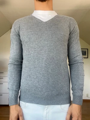 Grå stickad tröja  - Grå stickad tröja från Hansen & Jacob tillverkad i 70% bomull, 20% nylon och 10% silke. Strl S inga defekter. Modellen är 178 cm och väger 77 kg. Hör gärna av dig vid frågor!