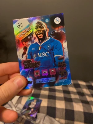 Match Attax fotbollskort Napoli - Säljer ett Match Attax fotbollskort med en spelare från Napoli. Kortet har färgstark design med holografiska effekter och texten 'Global Goalscorers' samt 'Limited Edition'. Perfekt för samlare av fotbollskort.