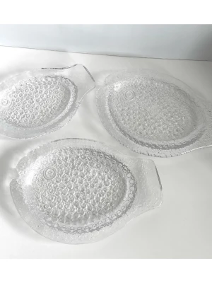 3 fiskformade glasfat - ”Vickning” av Uno Westerberg för Pukeberg Glasbruk  - Tre gedigna glasfat i form av fiskar från den populära ”Vickning" - serien, designad av erkände svenske glaskonstnären Uno Westerberg (1914-1985) för anrika glastillverkaren Pukeberg Glasbruk under 1970-talet. Fiskformade uppläggningsfat av pressglas med ett bubbligt mönster. Tillverkat av Pukeberg Glasbruk. Klassiska fat för servering eller som dekorativa föremål. Två större fat som är 26x17cm och ett mindre fat som är 23x14cm. Ett stycke svensk designhistoria i glasform. Mycket gott skick!