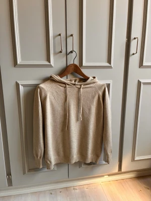 Beige stickad hoodie med huva - Säljer en beige stickad hoodie. Vet intr vad det är för tyg men det är väldigt mjukt iallafall 