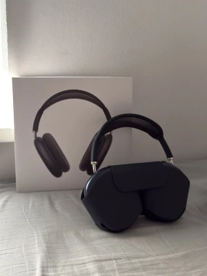 Midnight blue AirPods Max - Stilrena svarta AirPods Max hörlurar med mjuka öronkuddar och metallbåge. Designen är modern och minimalistisk, med mesh-material i huvudbandet för extra komfort. Levereras med ett matchande skyddsfodral.