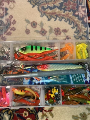Fiskedrag och beten i ask - Säljer en ask fylld med olika fiskedrag. Innehåller jiggar, wobblers, spinnare och mjuka gummibeten i grönt, orange, gult och rött. Dom flesta är aldrig använda och ca 6 är använda sedan innan. Det ingår 39 olika fiskedrag och 53 olika krokar/tyngd med krok. Lådan ingår också.