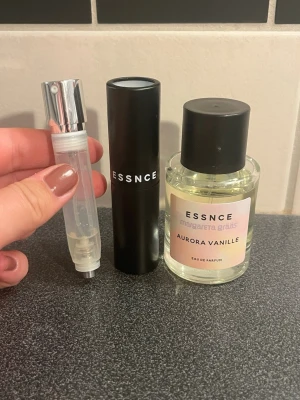 Aurora Vanille parfym från Essnce - Aurora Vanille Eau de Parfum från Essnce, skapad av Margareta Grääs. Flaskan är genomskinlig med svart lock och stilren etikett. Medföljer även en svart resespray och påfyllningsbar miniflaska, som är påfylld med doften. Se bild för mängd. 