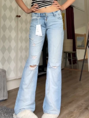 Ljusblå bootcut jeans med slitningar - Säljer ett par jeans som är slutsålda från Gina tricot!