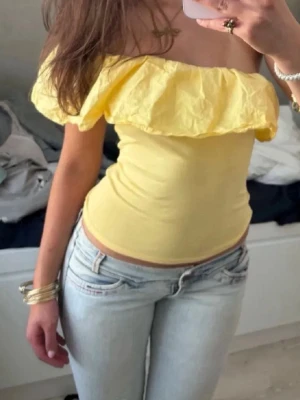 Gul offshoulder topp med volang - Toppen är från Kappahl, men säljs inte längre. Säljer även en i rosa💗 Det är barnstorlek (152 och 158) men eftersom att de är så pass stretchiga och ”stora” i storleken så sitter de perfekt på mig som är ca 165 och bär xs.