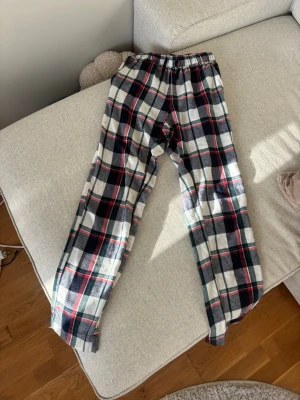 Rutiga pyjamasbyxor i flanell - Mysiga pyjamasbyxor i mjuk flanell med klassiskt rutigt mönster i vitt, svart, rött och grönt. Byxorna har resår i midjan och snörning för extra komfort. Perfekta för chillkvällar hemma. Från Ullared, i storlek 170. Men passar även en Xs. De har tecken på användning , lite noppriga. Annars fint skick
