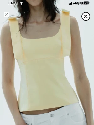 Gul topp från Zara  - Trendig ljusgul linnetopp med breda axelband och fyrkantig urringning. Toppen har en figurnära passform och är tillverkad i ett slätt material som ger en stilren look. Perfekt för varma dagar och enkel att styla med jeans eller kjol. Säljer pga att den inte passade mig.💗