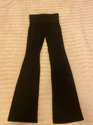 Svarta bootcut leggings - Säljer ett par svarta leggings med bootcut-modell och hög midja. De har en bred linning upptill och är tillverkade i ett stretchigt material som sitter skönt. Perfekta för dig som gillar en trendig och bekväm stil.